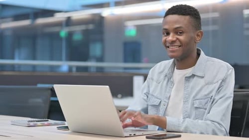 Man Typing at Laptop in Modern Office Setting