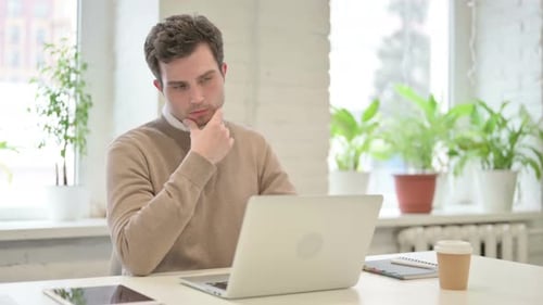 Man Thinking While Working on Laptop in Office