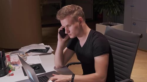 Man Working at Desk While Talking on Phone