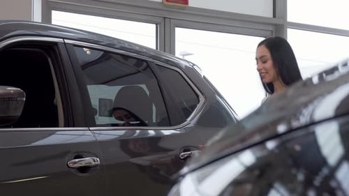Woman Smiling To the Camera, While Examining Cars on Sale at the Dealership