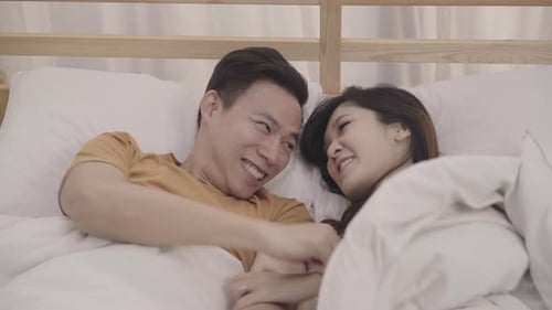 Couple heureux de passer un moment amusant à jouer sous une couverture ensemble sur le lit à la maison.
