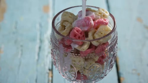 Milk Being Poured on Cereal in a Glass Cup