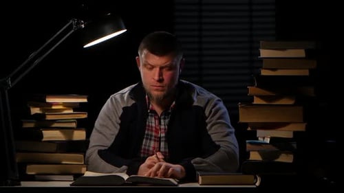 Guy in the Lamplight Records Information on Paper and Crumples It. Black Background