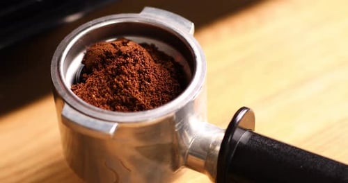 Ground Coffee Being Placed in Portafilter with Spoon