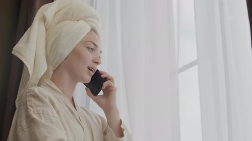 Woman in Robe Talking on Phone by Window