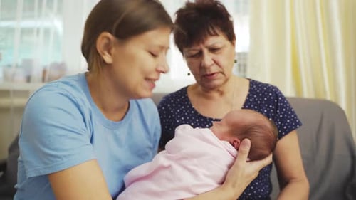 Three Generations: Women Adore Newborn Baby Indoors