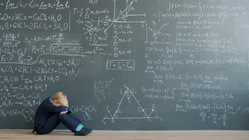 Sad Child Sitting on Floor Near Chalkboard Wall Thinking Solving Problem Alone