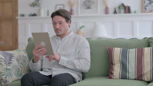 Man Using Tablet Device While Sitting on Couch