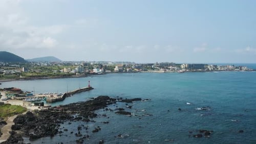 The scenery of a small port village with a blue sea and sky spread out. Jeju