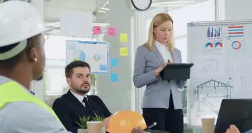 Mujer que celebra una reunión con su colega serio, hábil y barbudo y su equipo profesional diverso