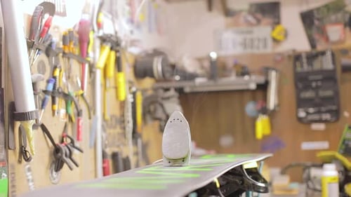 Iron Is Heating Up And Smoke. Snowboard Maintenance And Repair Concept.
