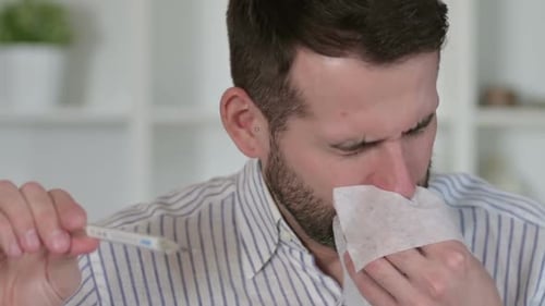 Sick Man Holding Thermometer and Tissue