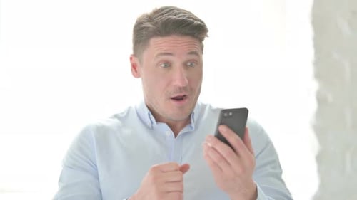 Man Cheers Success After Using Smartphone
