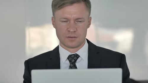 Smiling Man Working on Laptop in Office