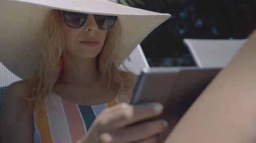 Stylish Woman Using Tablet by Tropical Pool