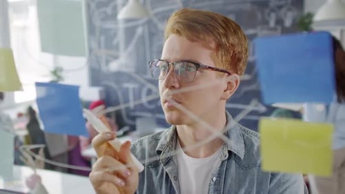 Young Adult Drawing Diagram on Clear Board