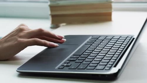 Woman Using Laptop Trackpad Near Window