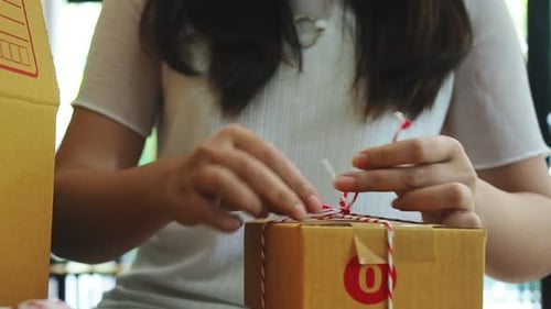 Young Adult Tying String on Shipping Box