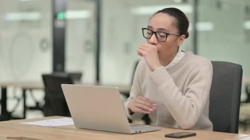 Woman Coughing while Working on Laptop at Desk