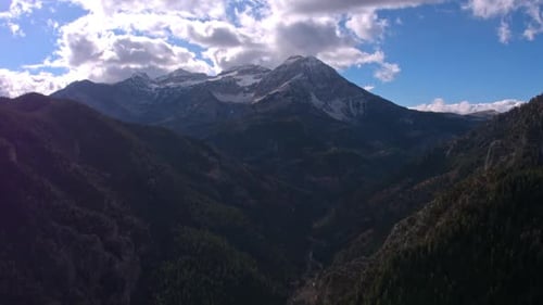 Vista aérea movendo-se sobre camadas de montanhas em direção a um pico de montanha nevado