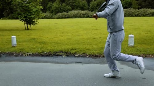 Man Running in Green Parkwoods Training and Look at Arm Clock