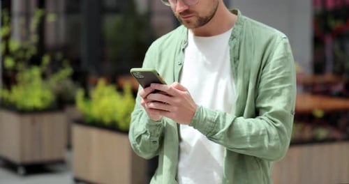 Young Man on City Street with Modern Smartphone in Hands