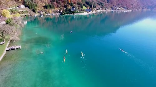 Three kayakers paddle in a scenic mountain lake.