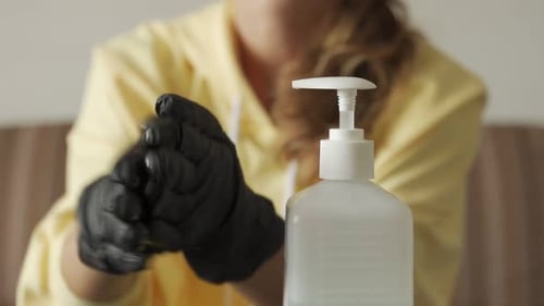 Woman Hands in Black Gloves Cleaning Hands with Sanitizer in Bottle Close Up
