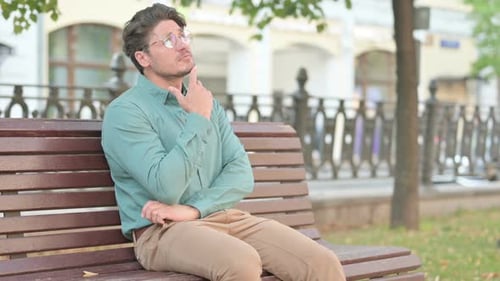 Thoughtful Man Sits on a Park Bench Pondering