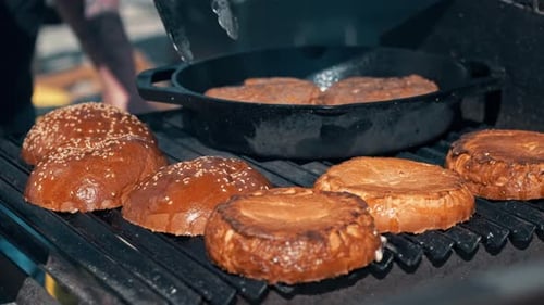 Frying patties and burger buns in a frying pan and grill. BBQ, slow motion