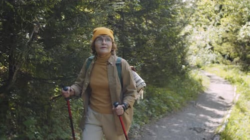 Senior Woman Walking with Trekking Poles in Park