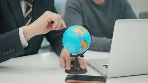 Senior Man CEO bei einem Geschäftstreffen mit einem Kollegen. Hand dreht den Globus