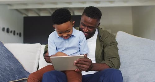 Father and Son Smiling While Using a Tablet