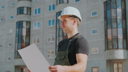 Construction Worker Inspects Blueprint at Building Site