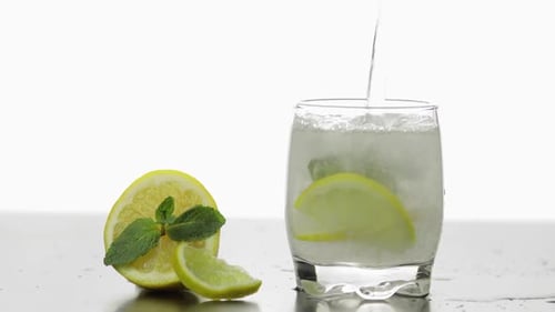 Sparkling Beverage Poured Into Glass with Lemon and Mint