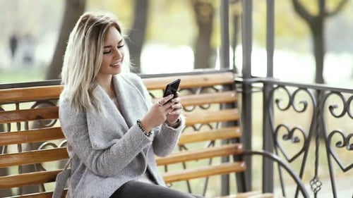 Portrait of a Young Beautiful Business Woman with a Mobile Phone in the Park