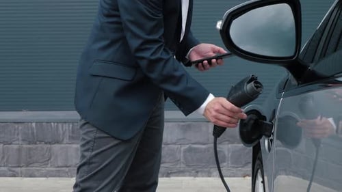 Man Charging Electric Vehicle in Urban Setting