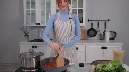 Woman Cooking Tomatoes and Peppers in Bright Kitchen