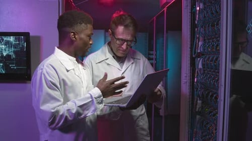 Technicians in Lab Coats Working in Data Center