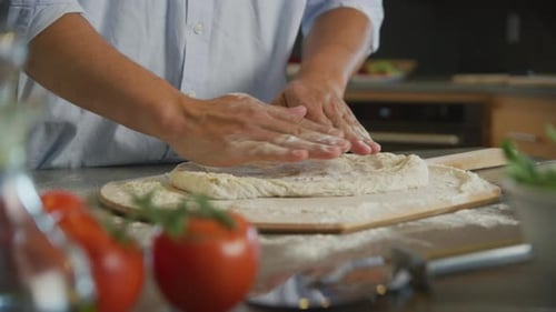Person Kneading Pizza Dough in Kitchen