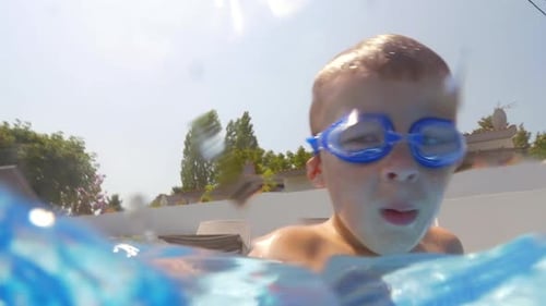 Child Swims Underwater in Swimming Pool Wearing Goggles