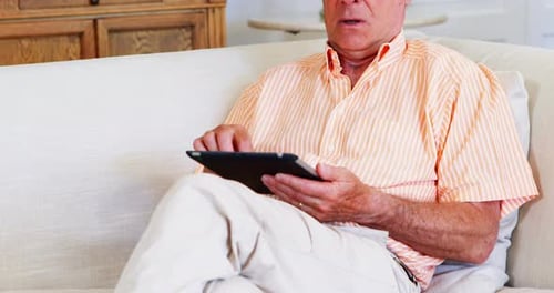 Senior Man Using Tablet on Comfortable Couch