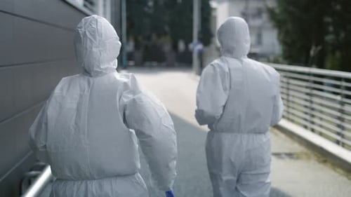 Hazmat Suits Walking Along Urban Street