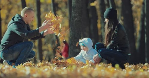 Happy Family Playing with Autumn Leaves in Park
