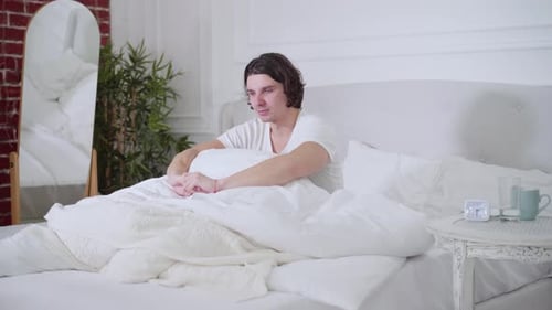 Man Wakes Up and Stretches in Bed