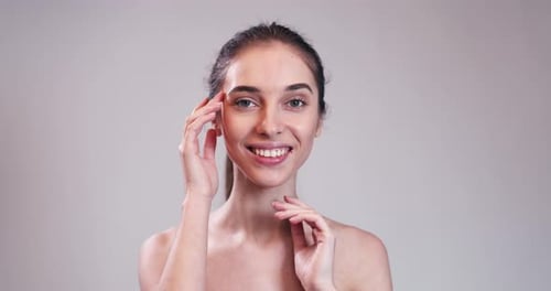 Woman Touching Her Face and Smiling in Studio