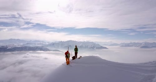 Aerial drone view of two mountain climbers on top of a snow covered mountain.