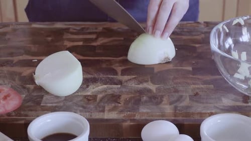Mincing yellow organic onions on wood cutting board