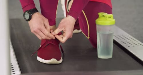 Man Tying Running Shoe on Treadmill