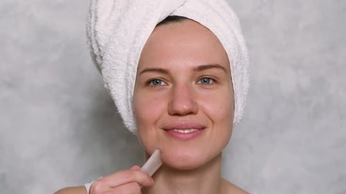 Woman Using Gua Sha Facial Tool on Face